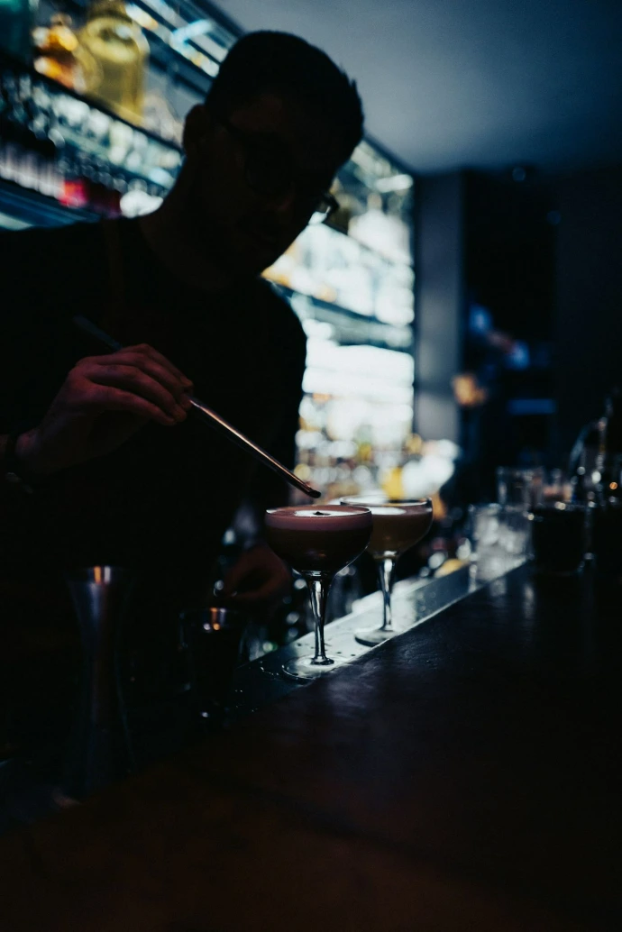 A man sitting at a bar making a drink